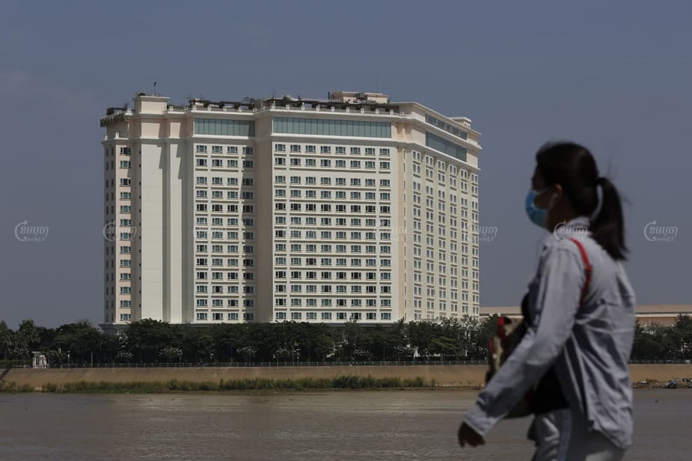 A woman walks on riverside on November 8 across from Sokha Phnom Penh Residence hotel, where families who are at risk of Covid-19 have started to quarantine. Panha Chhorpoan