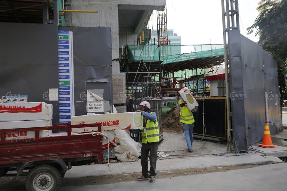 Construction workers offload materials at a worksite in Phnom Penh on November 8. Panha Chhorpoan