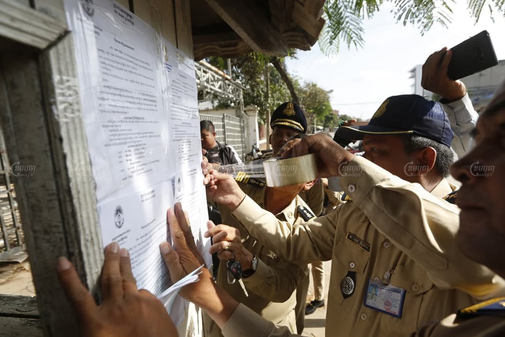 Phnom Penh police officials plaster court summons for former CNRP members at the party headquarters earlier this month for hearings that will be conducted on November 26. Panha Chhorpoan