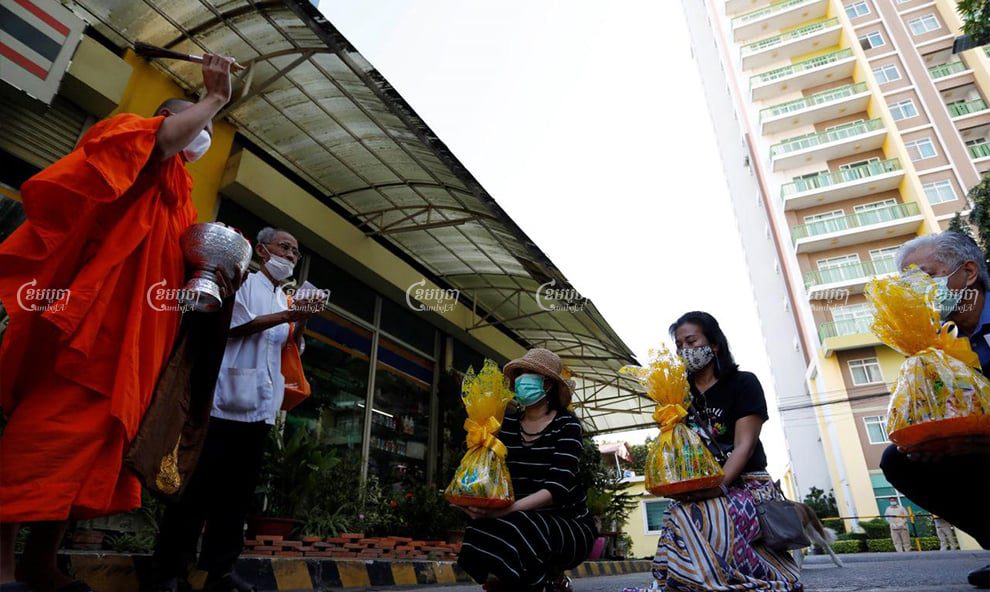 Missing Thai activist Wanchalearm Satsaksit’s sister, Sitanun Satsaksit (left), gets a blessing from monks on Friday, outside a condominium where her brother was allegedly abducted in June. Panha Chhorpoan