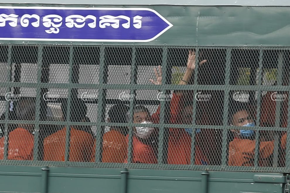 Former CNRP official Sok Chantha waves to photographers as he arrives at the Phnom Penh Municipal Court in a prison truck on Friday. Panha Chhorpoan