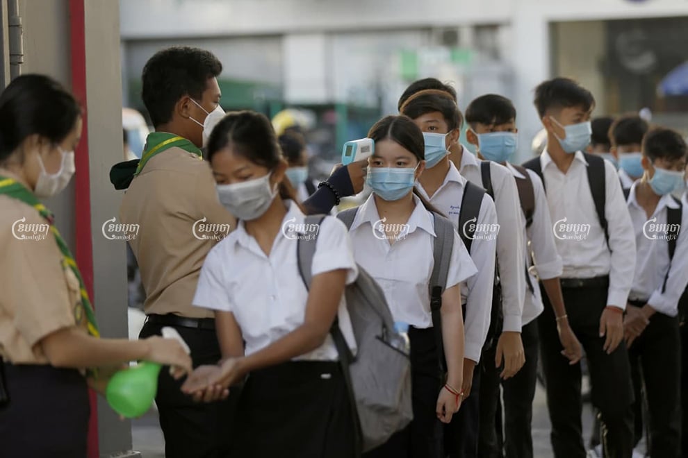 Students clean their hands as they return for the 2021 school year at Bak Touk High School in Phnom Penh on Monday. Panha Chhorpoan