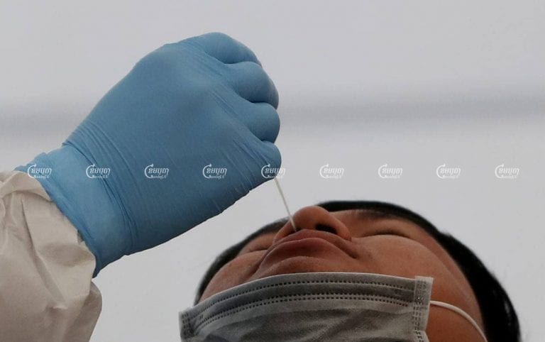 A healthcare worker swabs a man’s nasal cavity for a COVID-19 test on Tuesday at Phnom Penh’s Chak Angre Health Center. CamboJA/ Pring Samrang