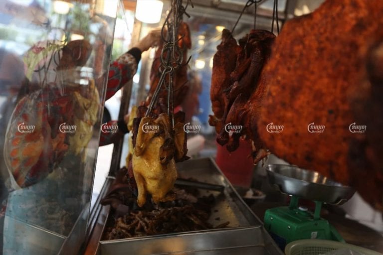 Before the start of the night's curfew, a vendor prepared roast duck, chicken and pork for sale at a street stall in Phnom Penh, April 2, 2021. CamboJA/ Pring Samrang