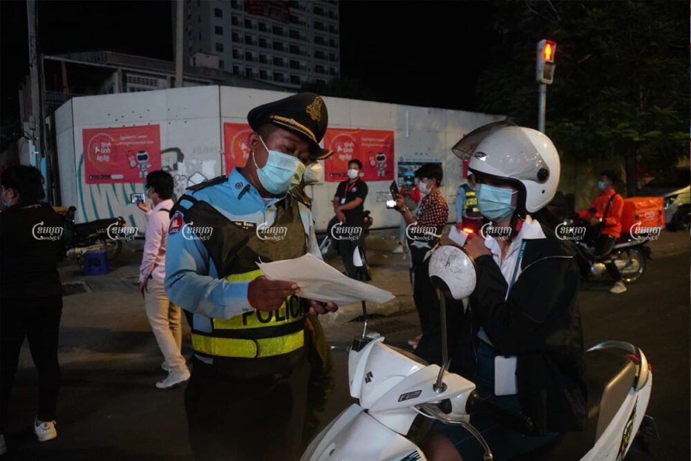 Motorists show official exemption letters to Phnom Penh police during curfew enforcement from 8 p.m. to 5 a.m., April 1, 2021. Panha Chhorpoan