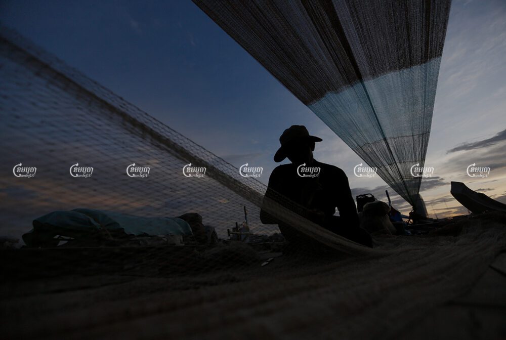 A fisherman repairs his fishing net on the Tonle Sap River in Phnom Penh, August 14, 2016. CamboJA/ Pring Samrang