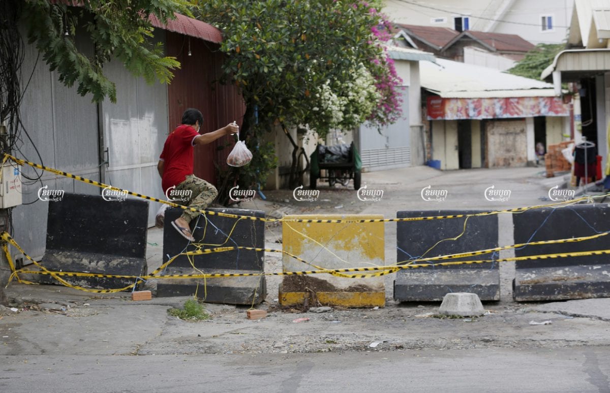 A man crosses a barricade blocking a Phnom Penh red zone, April 30, 2021. CamboJA/ Panha Chhorpoan