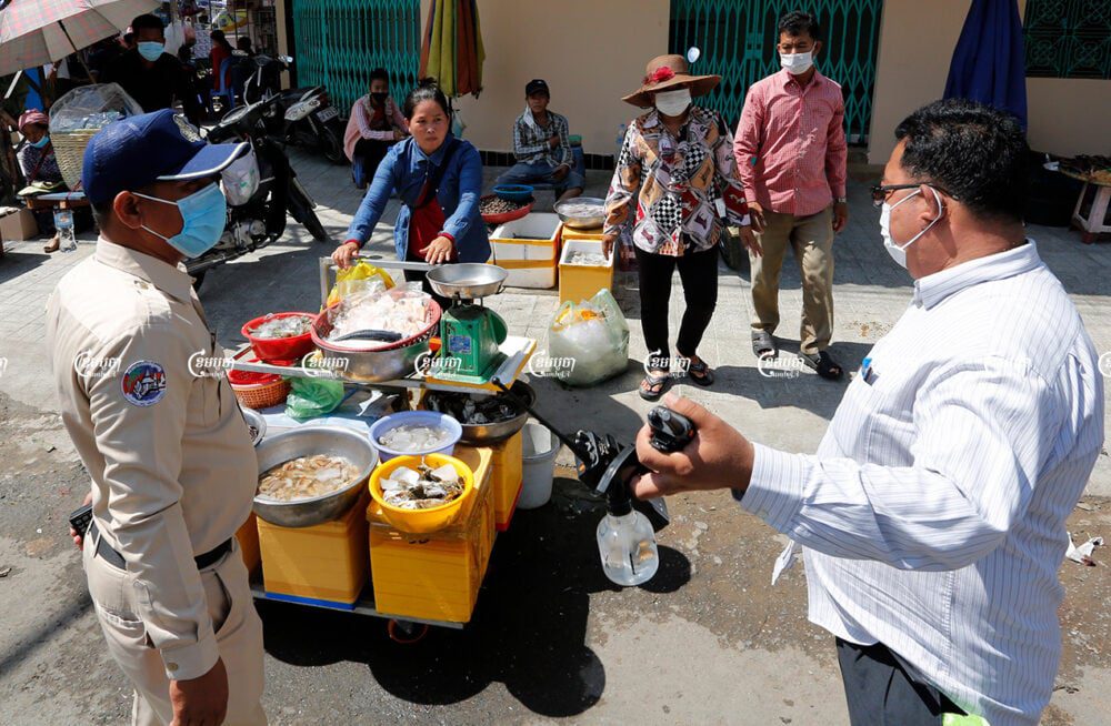 Local authorities order a vendor to move away from her selling place near Phsar Kadnal in Daun Penh district, May 20, 2021. CamboJA/ Panha Chhorpoan