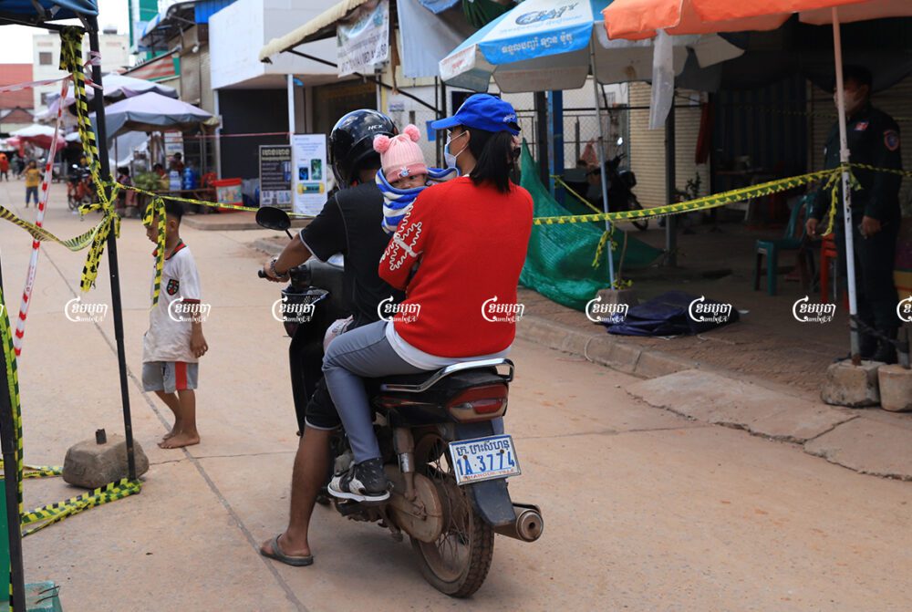A man drives his family across a barrier placed at the lockdown zone at Siem Reap's Sala Kamroeuk commune, which was affected by COVID-19. July 26, 2021. CamboJA/ Panha Chhorpoan