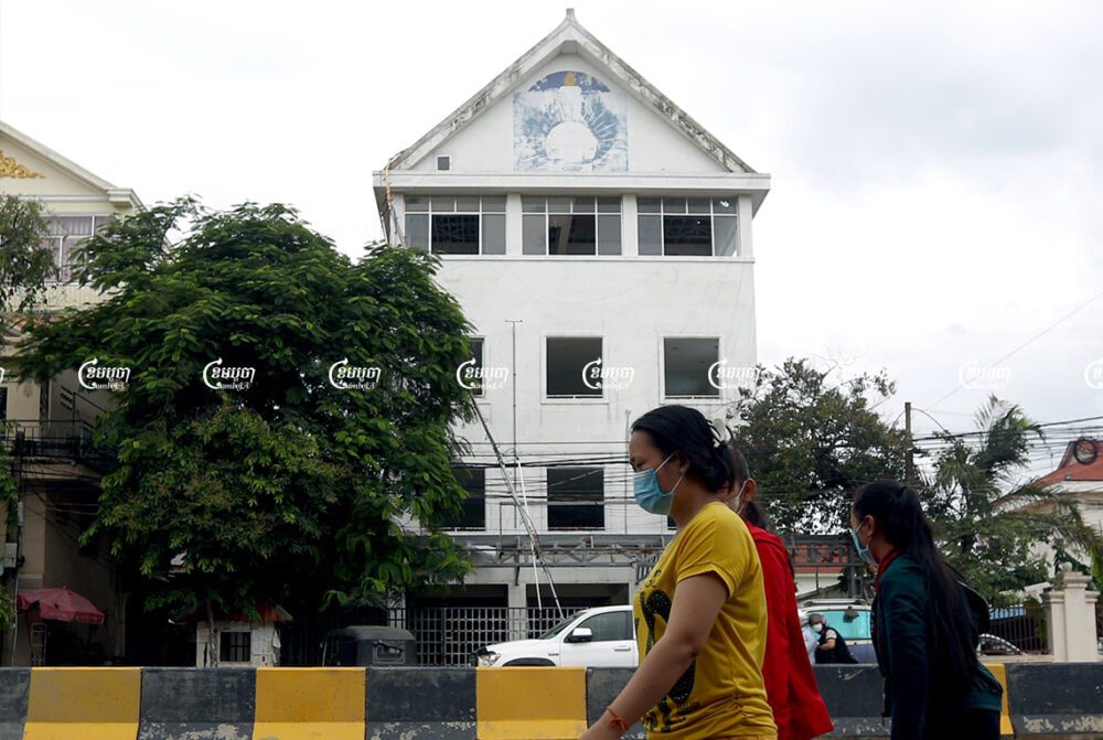 Pedestrians walk past the former Cambodia National Rescue Party headquarters in Phnom Penh. Picture taken on May 24, 2021. CamboJA/ Pring Samrang