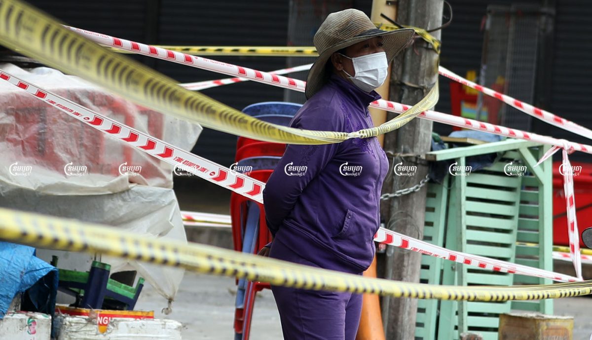 A woman stands in front of her home near the locked-down market in Phsar Chas commune, Daun Penh district in Phnom Penh, August 23, 2021. CamboJA/ Pring Samrang