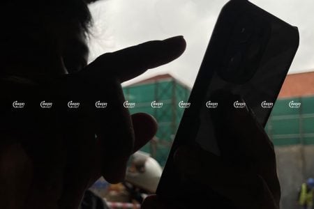 A man uses his smartphone at a coffee shop along a street in Phnom Penh, September 1, 2021. CamboJA/ Pring Samrang