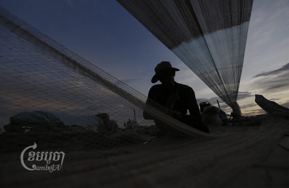 A fisherman repairs his fishing net on the Tonle Sap River. Picture taken August 14, 2016. CamboJA/ Pring Samrang