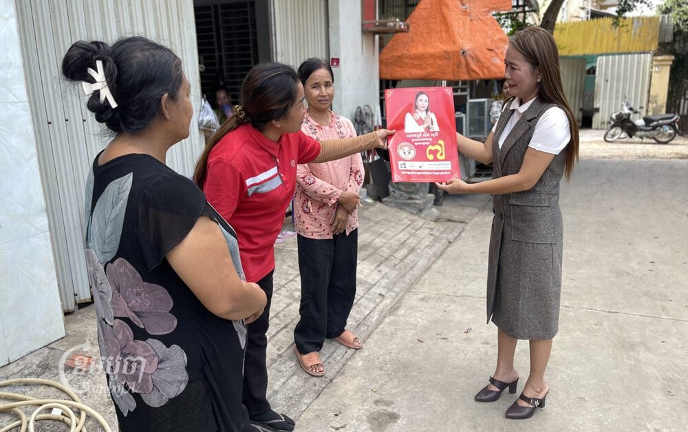Soeung Sothy, president of Women for Women Party, meets people in Phnom Penh’s Meanchey district which shows a leaflet of her party policy, June 23, 2023. CamboJA/Pring Samrang