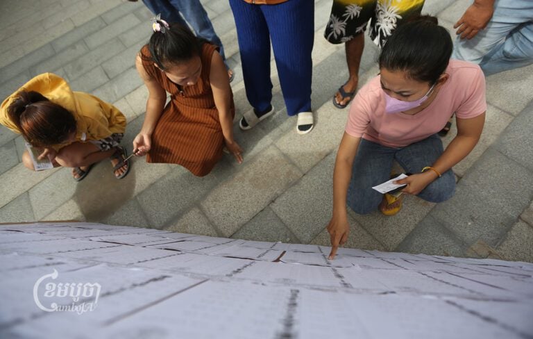 Voters look at their names on voter lists outside the polling station in Phnom Penh, July 23, 2023. (CamboJA/Pring Samrang)