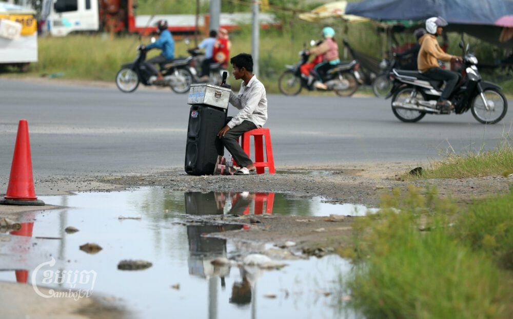 A man with disability sings for tips along a street on the outskirts of Phnom Penh on August 4, 2023. (CamboJA/Pring Samrang)