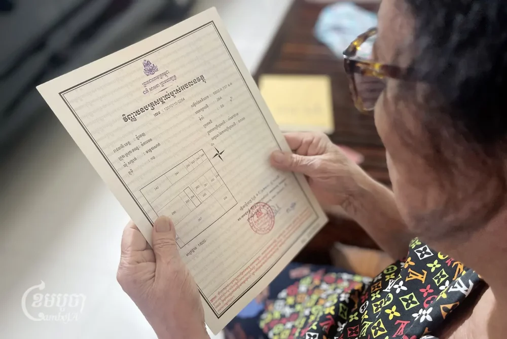 A woman looks at her land title certificate. CamboJA/Pring Samrang