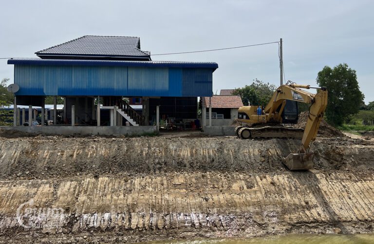 An excavator digs a canal near a wooden house located in Prek Sleng commune, on August 21, 2024. (CamboJA/Sovann Sreypich)