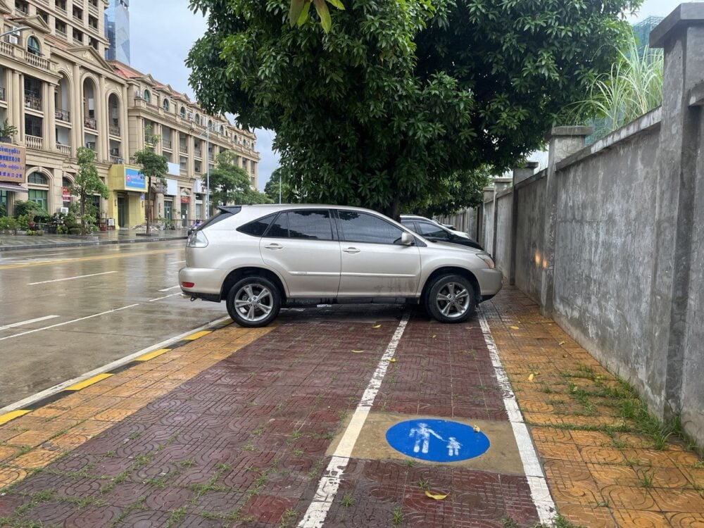 An SUV and several other cars parked on a sidewalk in Phnom Penh, blocking a clearly marked pedestrian lane on August 21, 2022. (Quinn Libson)