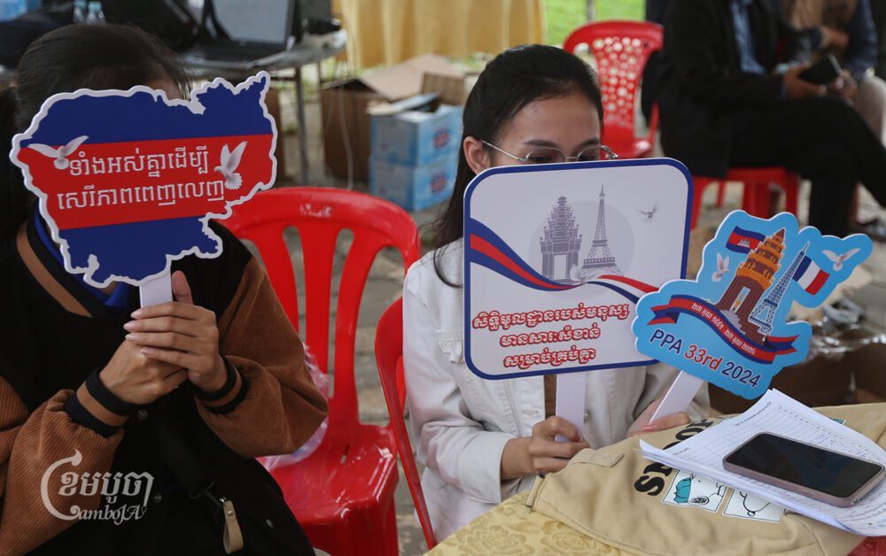 Participants hold up placards at the 33rd anniversary of the Paris Peace Agreements at Freedom Park in Phnom Penh on October 20, 2024. (CamboJA/Pring Samrang)