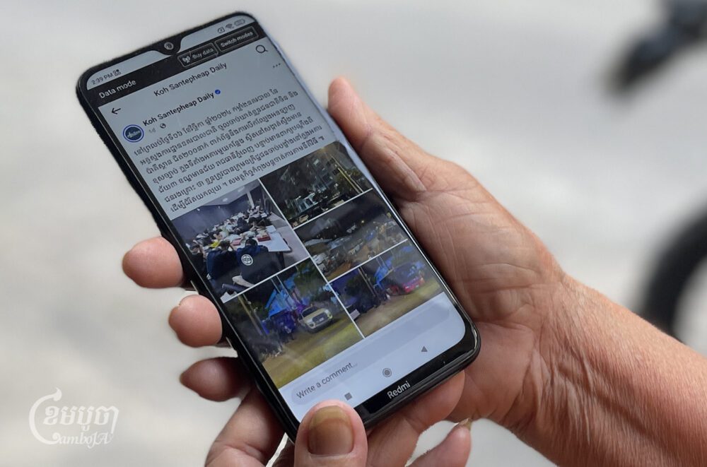A woman views a post about a raid on a scam compound in Phnom Penh on November 8, 2024. (CamboJA/ Pring Samrang)