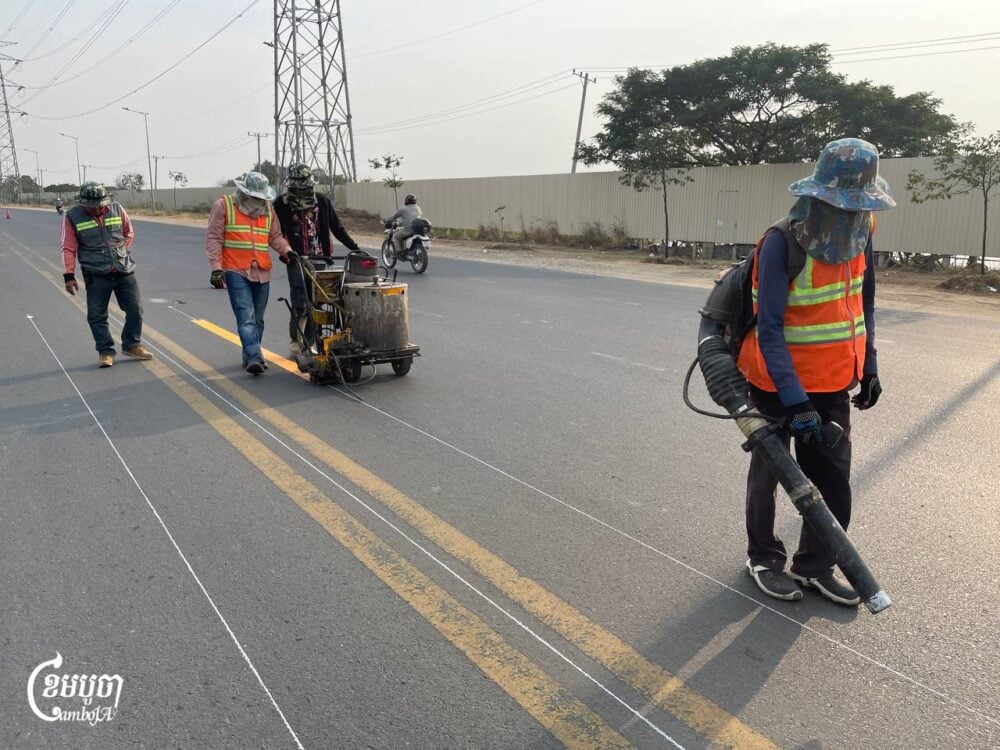 Workers paint a new traffic line to divide Hun Sen Boulevard, commonly known as "60 meters," before adding a concrete median, following several traffic accidents. Photo taken on Jan. 24, 2025. (CamboJA/Pring Samrang)
