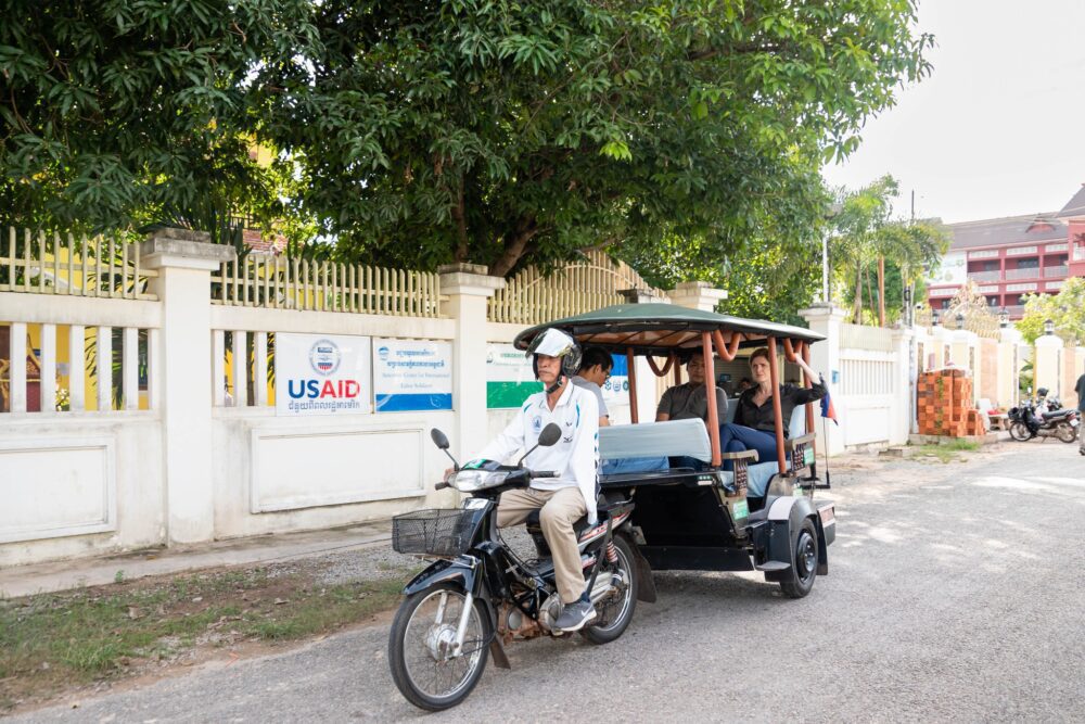 USAID Administrator Samantha Power rides a tuk-tuk past an office with a USAID signboard in Siem Reap during her visit to Cambodia in October 2024. Photo: USAID Cambodia