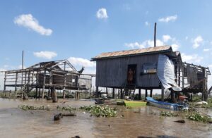 Houses stand in rising water following the construction of the Lower Sesan Dam II at the old Kbal Romeas village, Stung Treng province. Photo taken in February 2022. (International River)
