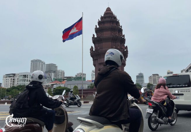 Motorists drive near the Independence Monument roundabout, which bears the Cambodian flag, in central Phnom Penh, July 21, 2025. (CamboJA/Pring Samrang)