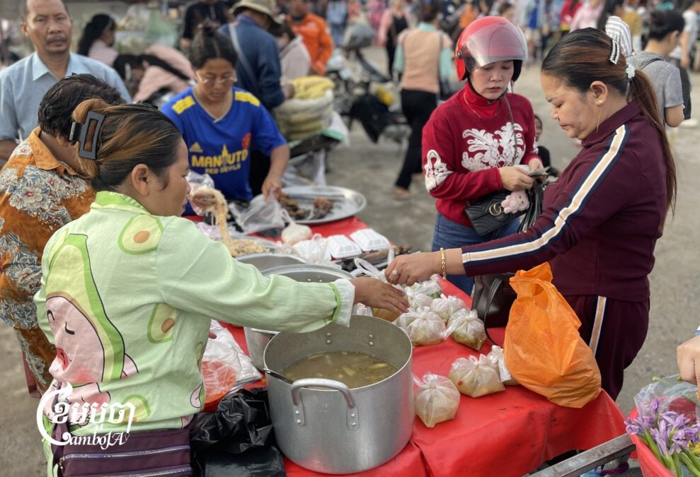 Garment workers buy food at a stall in front of a factory in Kandal province after arriving early in the morning before their shift. Sept. 3, 2025. (CamboJA/ Pring Samrang)