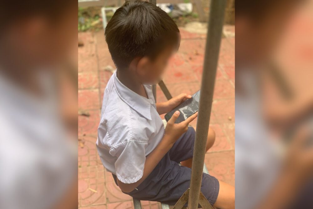 A boy uses his mother’s smartphone in Kampong Cham province. Sept. 3, 2025. (Photo: Chanleap Pin)