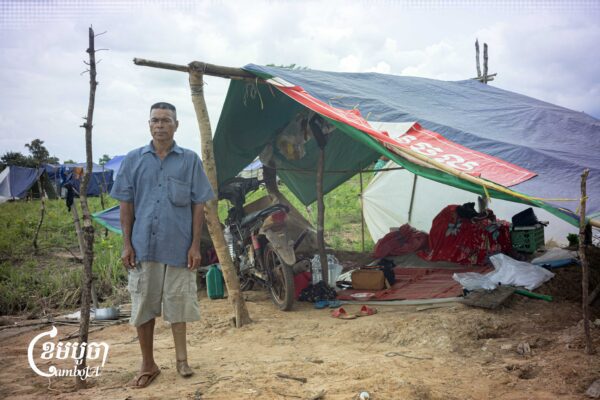 Nol Ny, 59, a former soldier who lost his left leg after stepping on a landmine, stands in front of his tent at a displacement camp in Preah Vihear province, September 6, 2025. (CamboJA/ Mech Choulay)