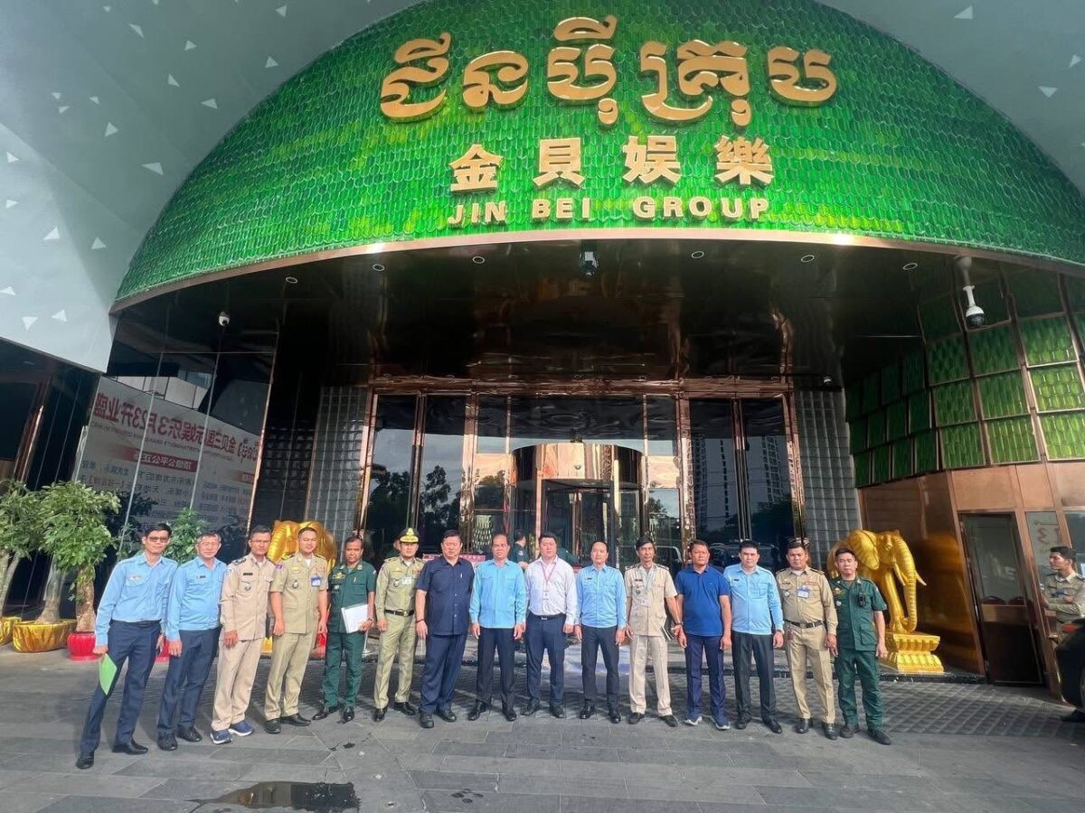 Authorities pose in front of a building with a Khmer and Chinese signboard bearing Jin Bei Group’s name on November 2, 2025. (CGMC Facebook page)