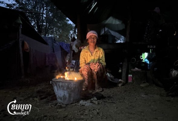 A woman is keeping herself warm by the fire in the early morning at a safe center in Preah Vihear province on December 17, 2025. (CamboJA/Va Sopheanut)